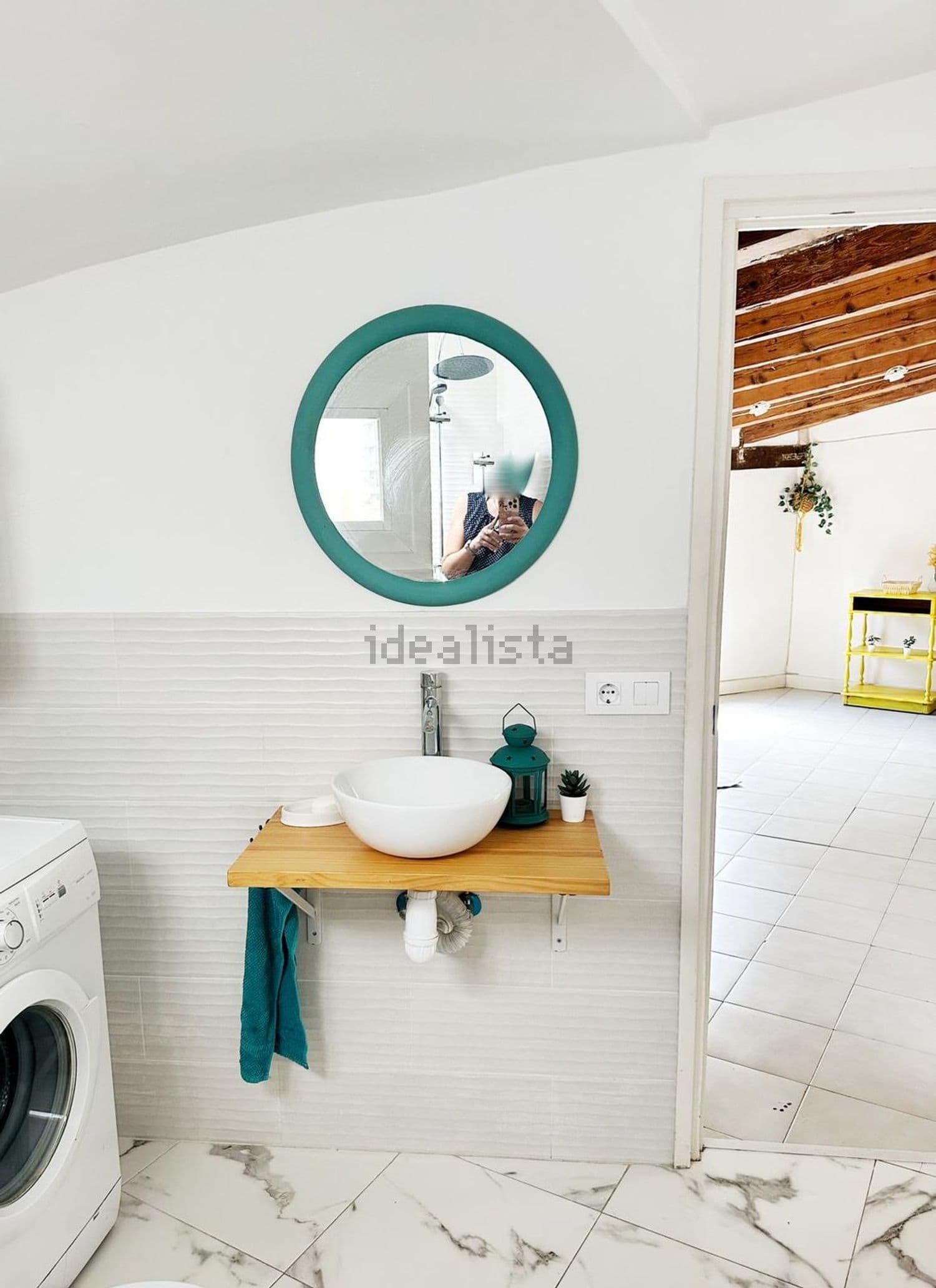 Baño con lavabo sobre encimera de madera, espejo redondo y lavadora