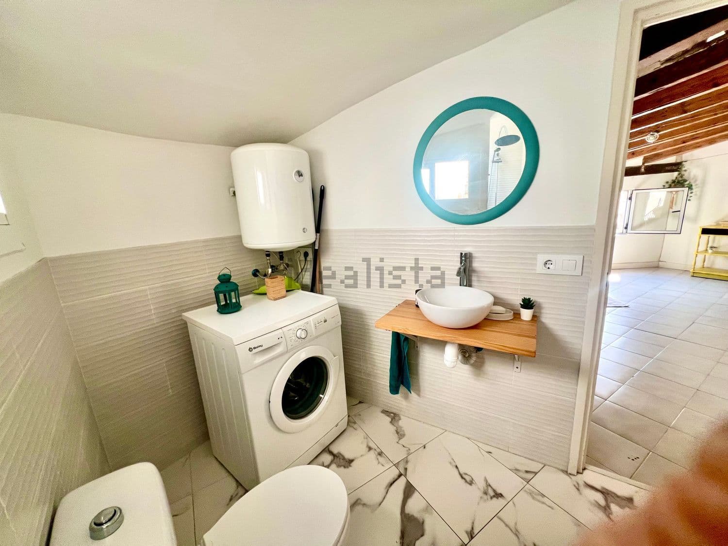 Lavabo con espejo redondo y lavadora bajo el termo