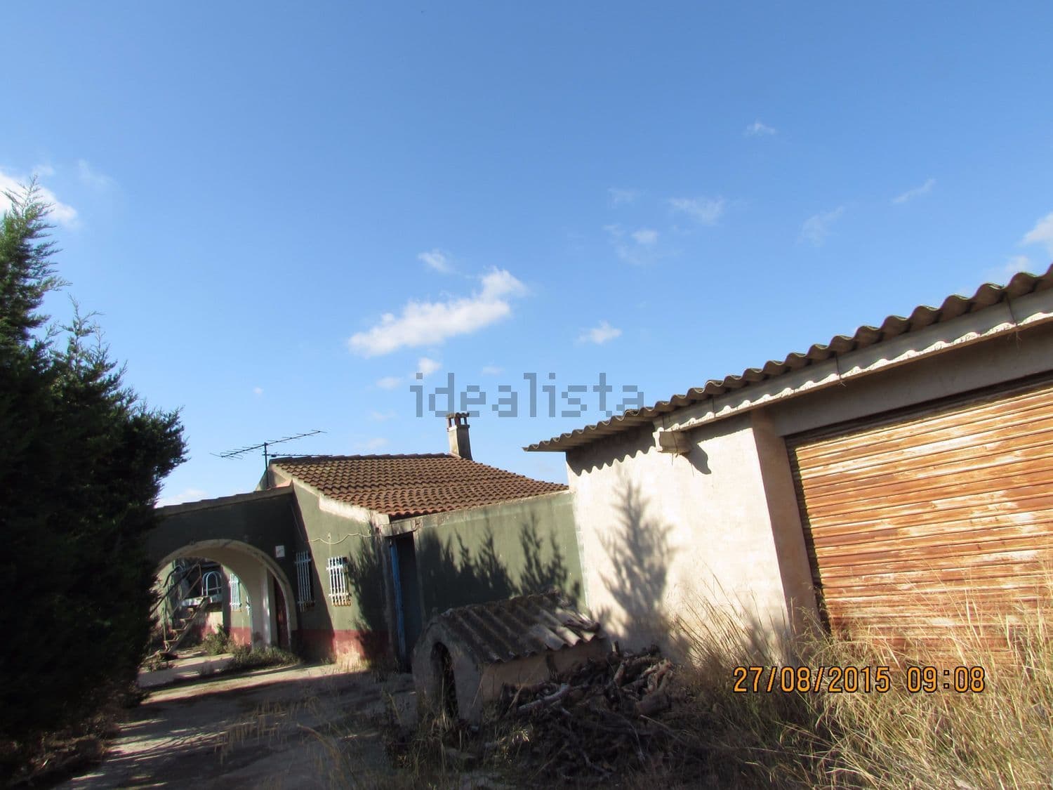 Fachada con puerta de garaje de madera y arco de entrada
