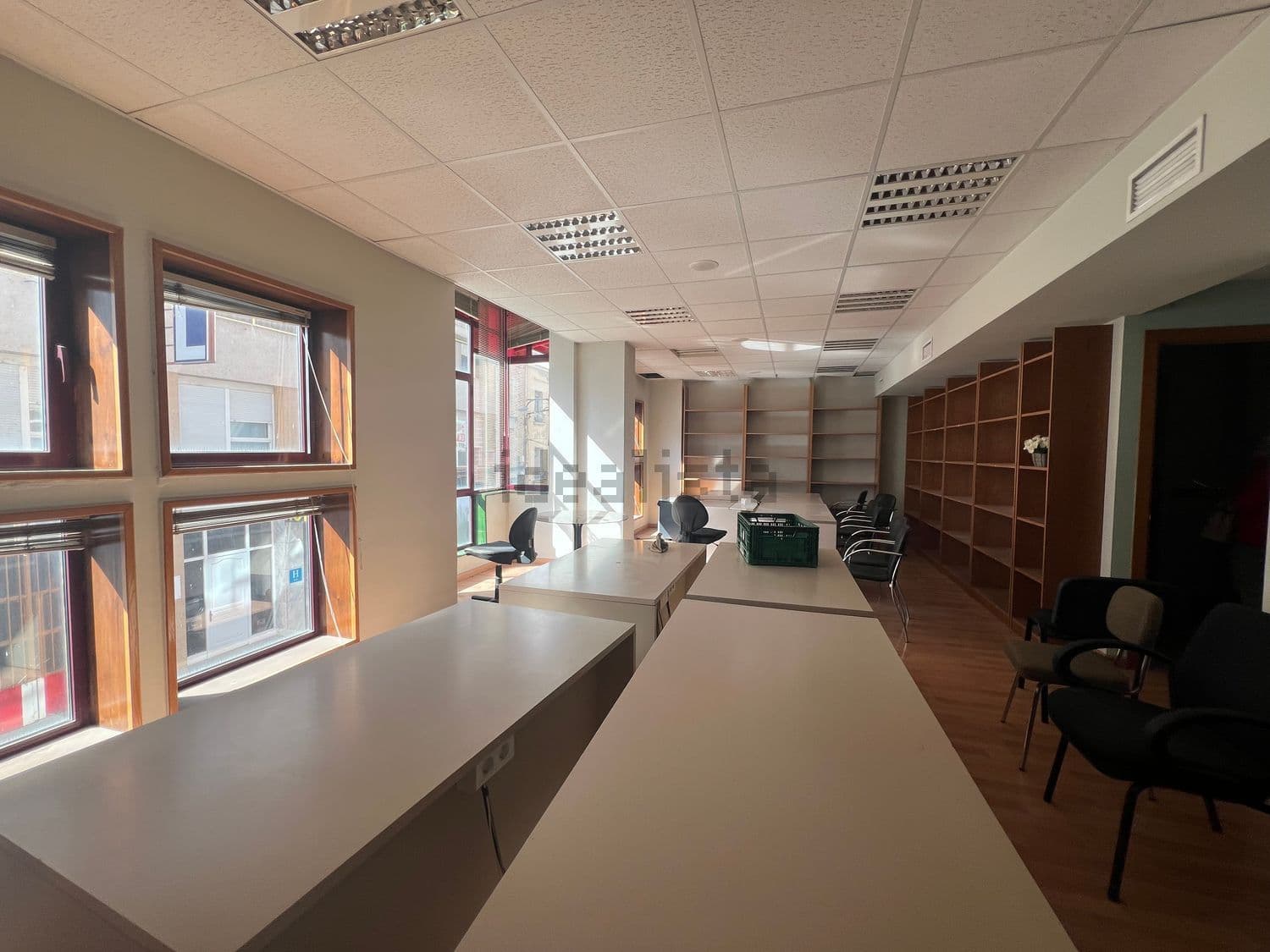 Sala amplia con mesas de trabajo, estanterías y ventanales
