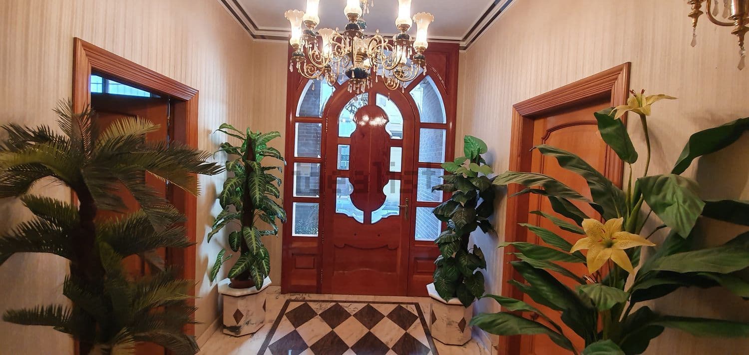Puerta de entrada de madera con vidriera y plantas a los lados