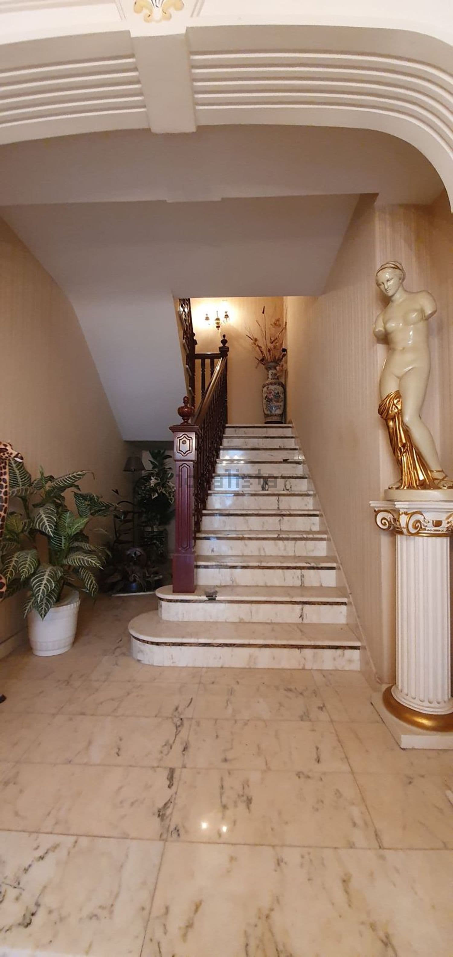 Escalera de mármol con barandilla de madera y una escultura
