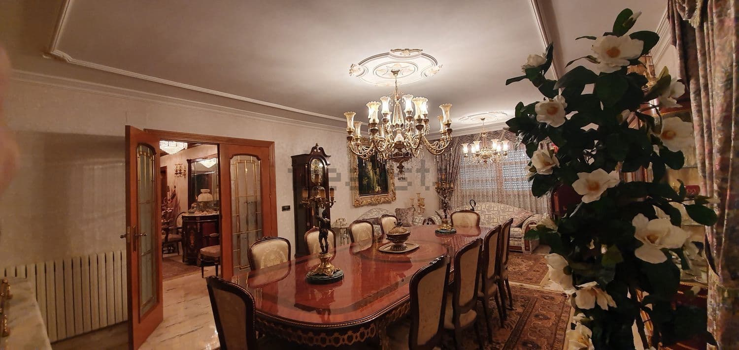 Comedor con mesa extensible, sillas tapizadas y lámparas de araña