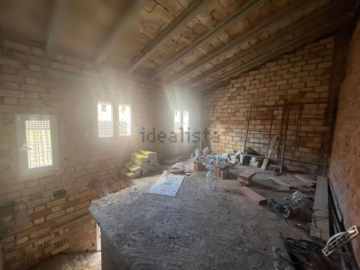 Planta bajo cubierta en obra con vigas de madera y ventanas