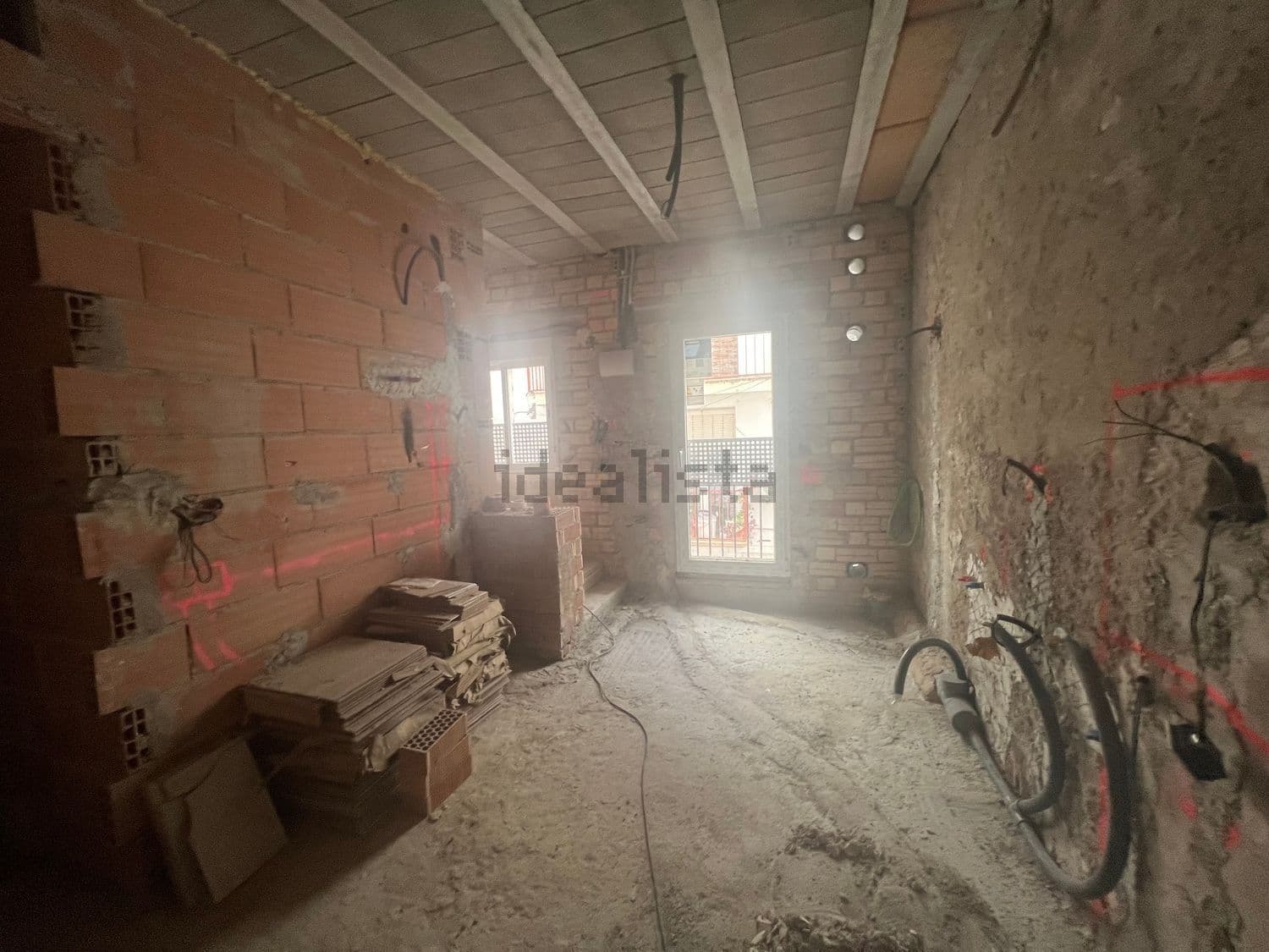 Estancia en obra con paredes de ladrillo y puerta balconera
