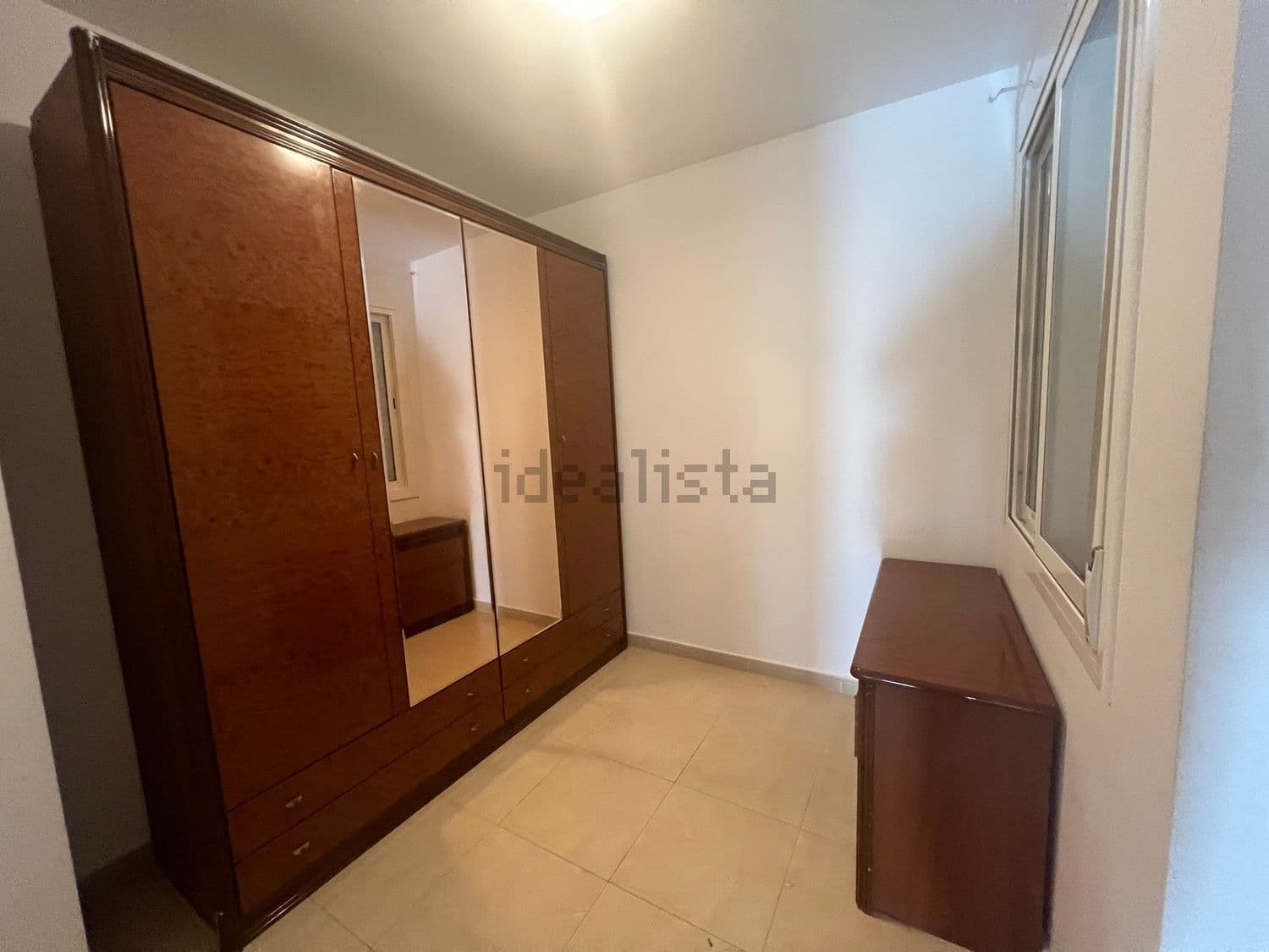 Dormitorio con armario de madera con espejo y cómoda