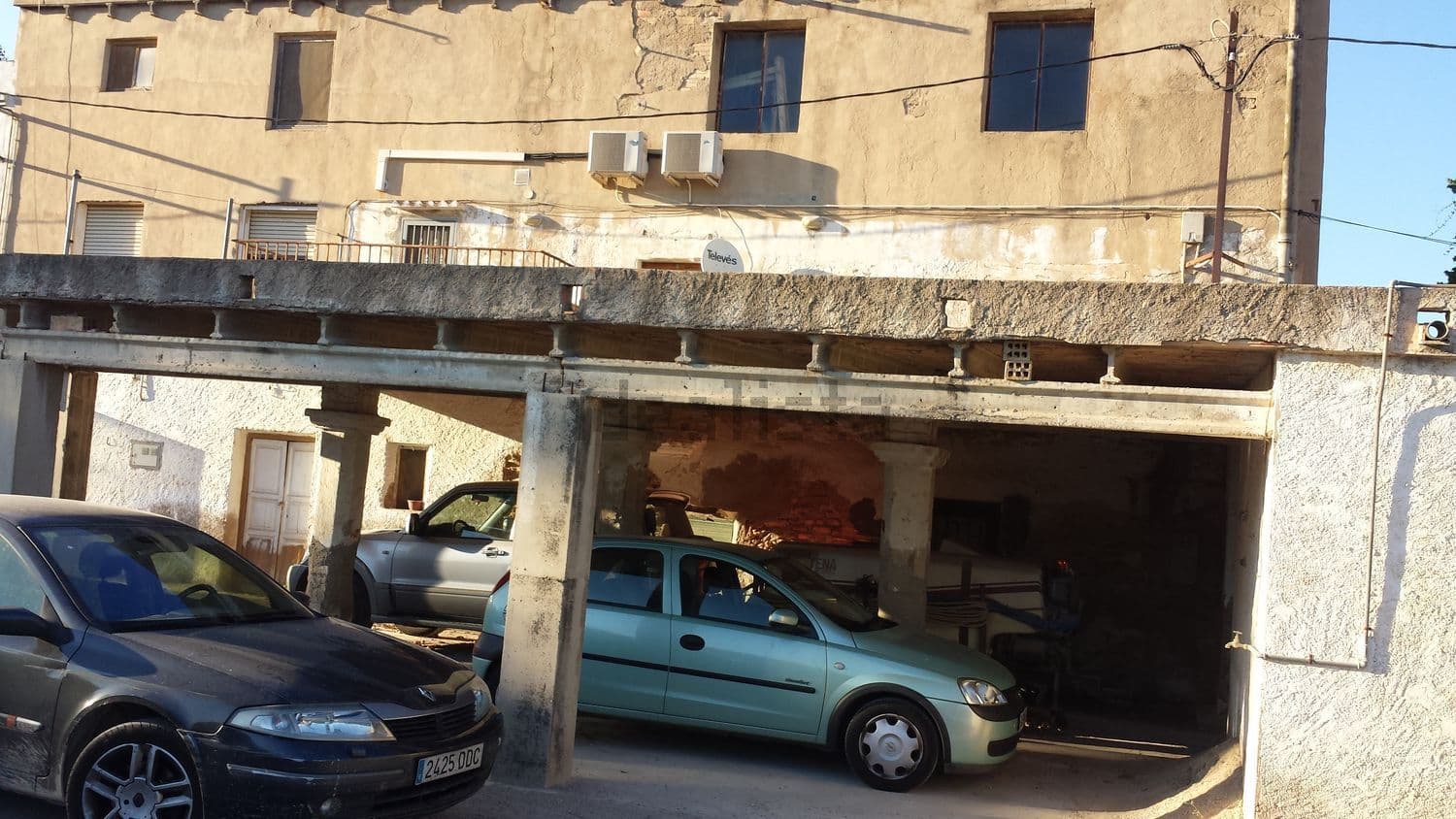 Garaje cubierto bajo la terraza con coches aparcados