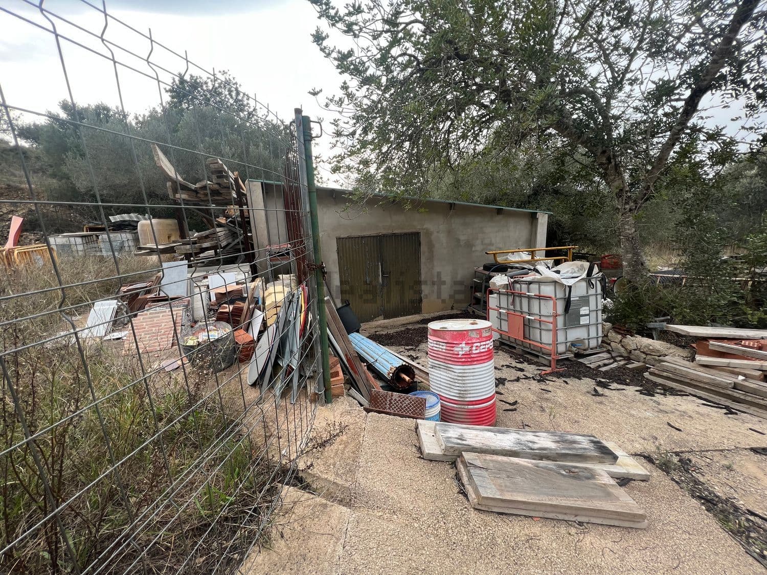 Almacén exterior con materiales de obra junto a la valla