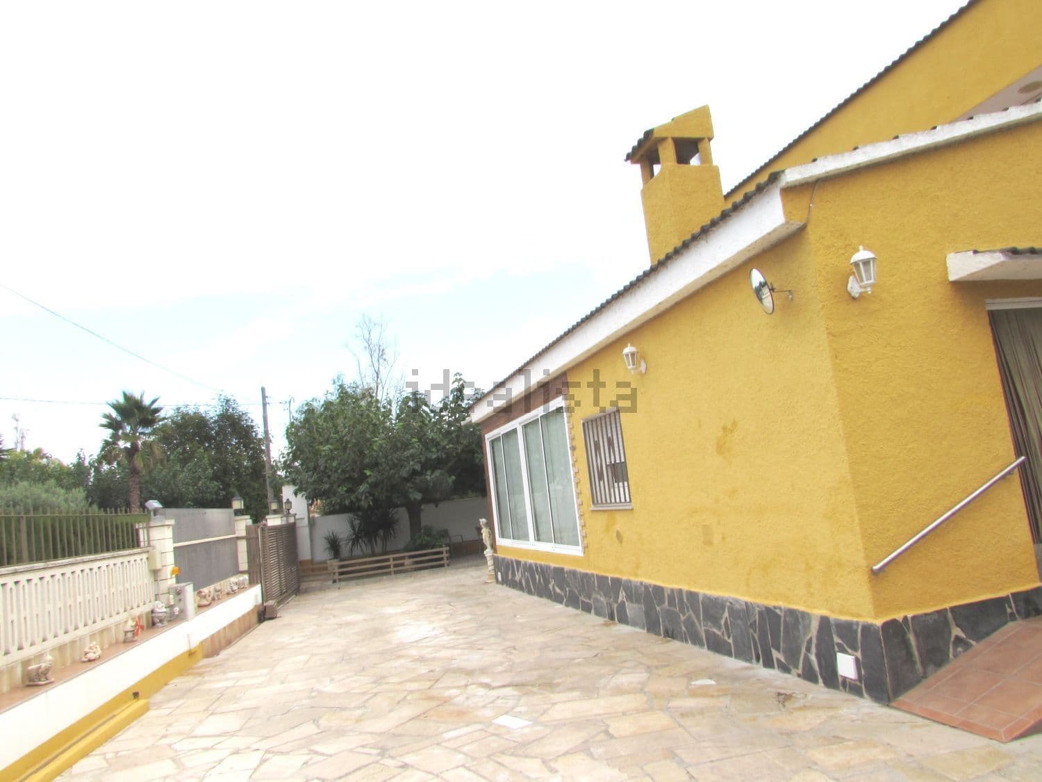 Fachada lateral del chalet con patio empedrado