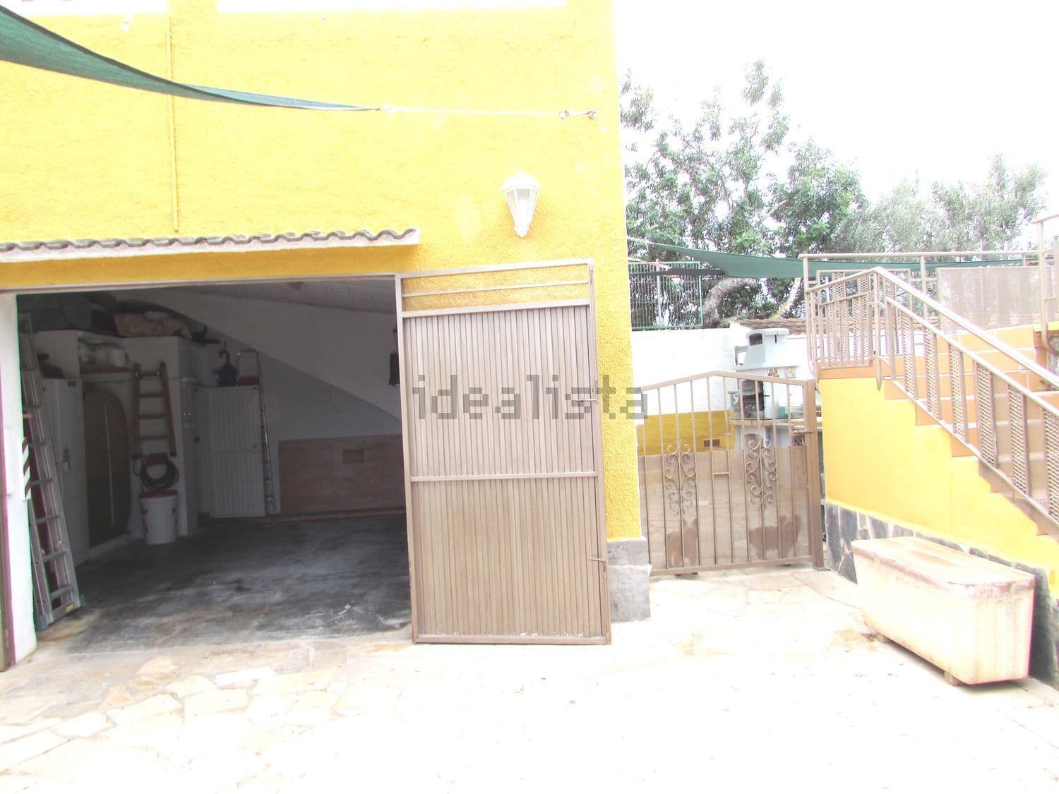 Garaje con puerta metálica y escalera exterior