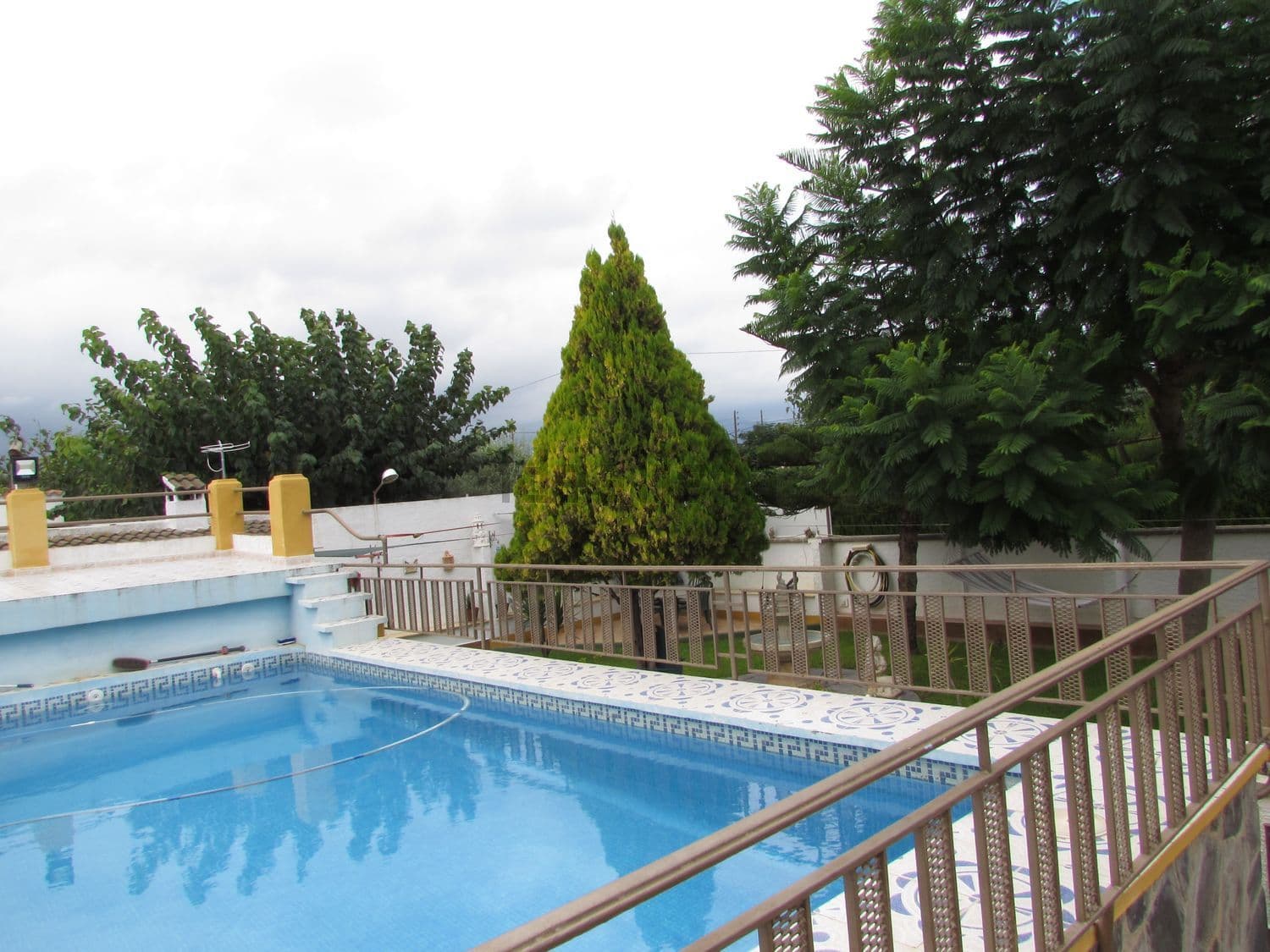 Piscina con barandilla y árboles al fondo