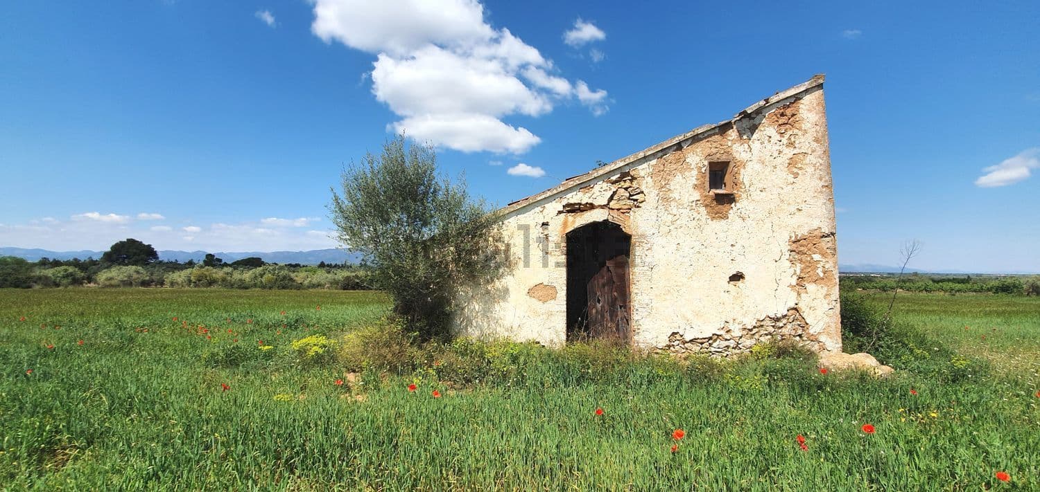 Casa de campo de piedra con puerta en arco entre la hierba