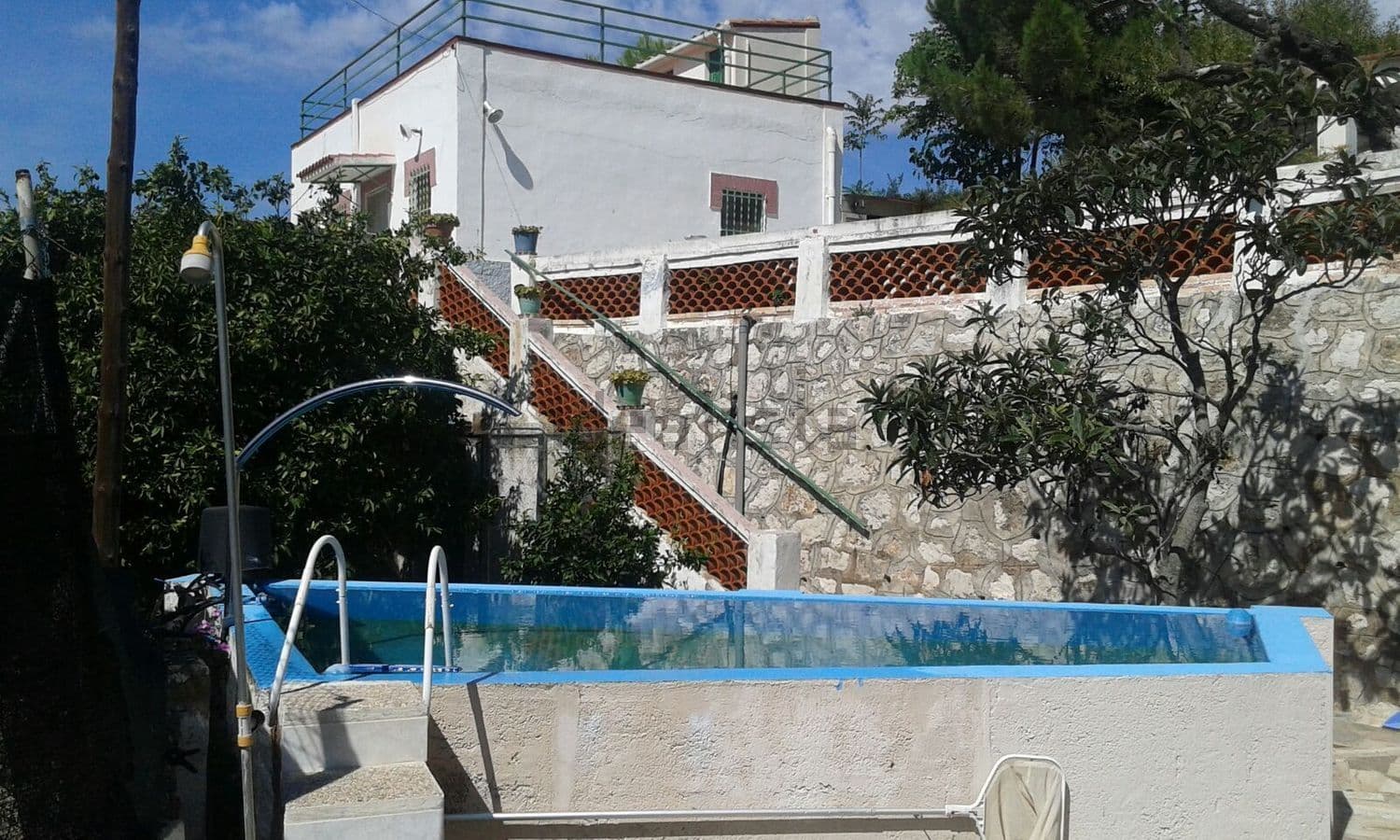 Piscina elevada con la casa y la escalera al fondo