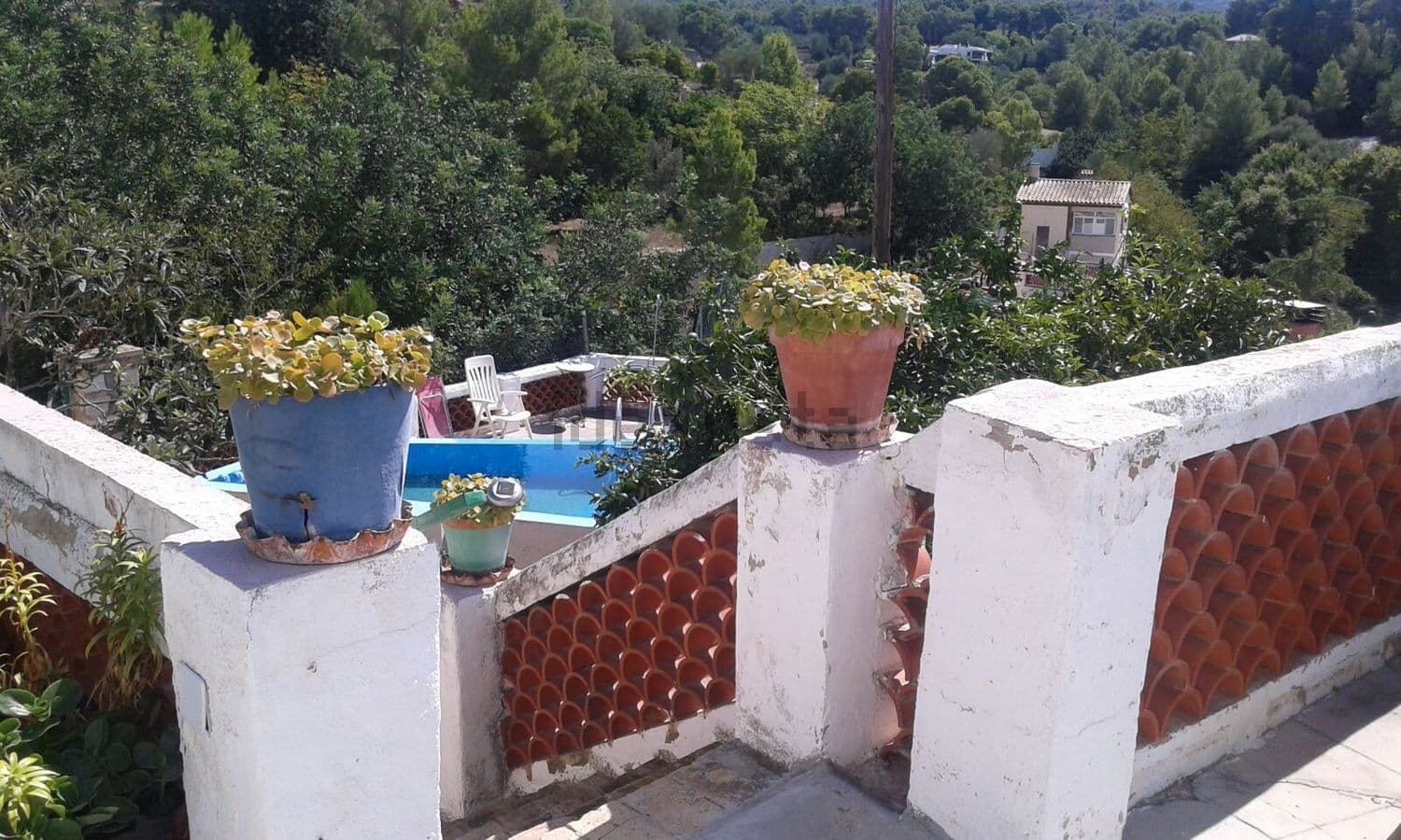 Terraza con macetas y barandilla de teja junto a la piscina