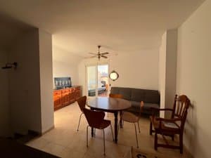 Salón comedor con mesa redonda, sofá y salida a la terraza