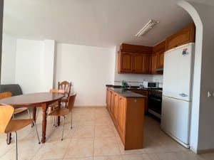 Cocina con muebles de madera, frigorífico y mesa