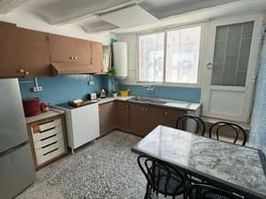 Cocina con muebles de madera, frigorífico y mesa