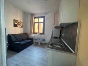 Salón con sofá y cocina abierta junto a la ventana