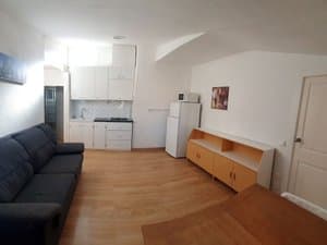 Salón cocina con sofá, frigorífico y mueble bajo