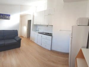 Cocina con placa, muebles blancos y frigorífico