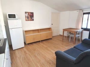 Salón con frigorífico, mueble y mesa junto a la ventana