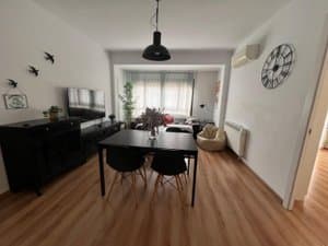 Comedor con mesa negra, reloj de pared y aire acondicionado