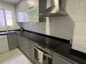 Cocina con encimera negra, placa y campana