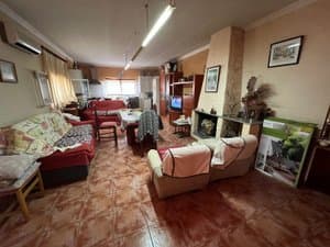 Comedor con chimenea, sofás y cocina al fondo