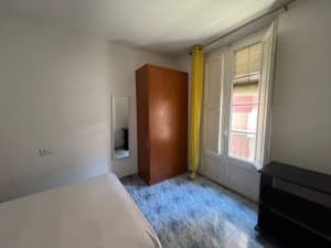 Dormitorio con armario de madera y puerta al balcón