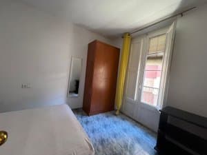 Dormitorio con cama y armario junto al balcón