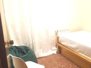 Dormitorio individual con cama y ventana con cortina