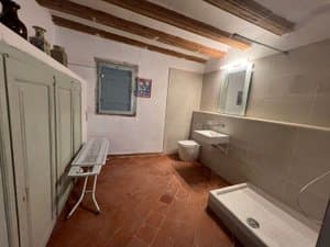 Baño con ducha abierta y suelo de barro
