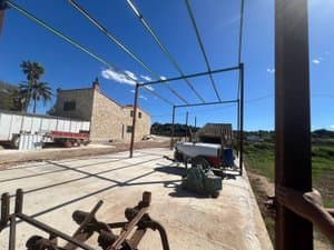 Explanada con pérgola metálica y maquinaria agrícola
