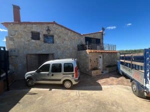 Casa de piedra con coche aparcado delante