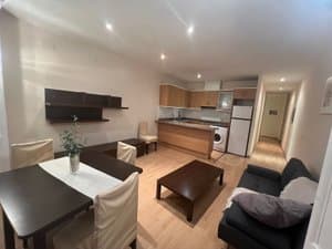 Salón con sofá, mesa de comedor y cocina abierta