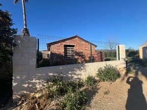 Caseta de ladrillo tras el muro de la finca