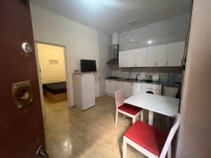 Estudio con cocina abierta, mesa y zona de dormitorio al fondo