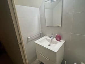 Baño con mueble de lavabo blanco y espejo