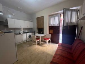 Salón con sofá rojo, cocina y mesa junto a la ventana