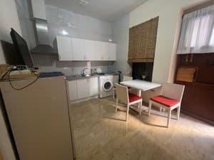 Cocina con lavadora y mesa con sillas rojas
