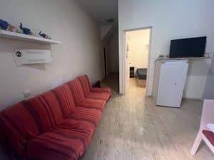 Sofá rojo y televisor con la puerta del dormitorio