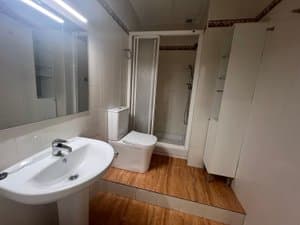 Baño con mampara de ducha y mueble auxiliar