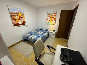 Dormitorio con cama, escritorio y cuadros