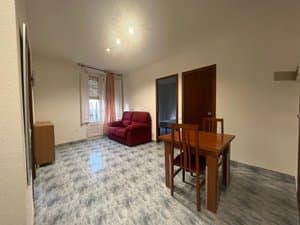 Salón con mesa, sillón y puertas a los dormitorios