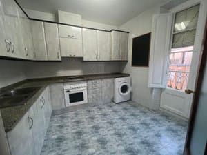 Cocina con encimera oscura y salida al balcón