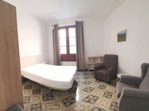 Estudio con cama, butacas y puertas balconeras