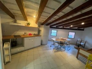 Cocina abierta bajo vigas de madera con mesa de comedor