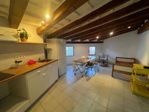 Cocina con encimera de madera y salón al fondo
