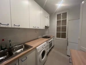 Cocina con muebles blancos, lavadora y fregadero