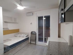 Estudio con cama, ventilador de techo y puerta al balcón